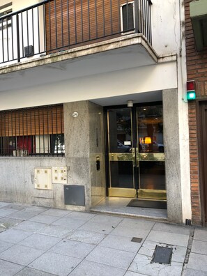 A building entrance with a glass door, a metal gate, and a small outdoor area with a bench. - Comfortable Apartment in Palermo (Buenos Aires)
