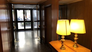 A hotel lobby with a polished floor, a reception desk with two lamps, and a glass door leading outside. - Comfortable Apartment in Palermo (Buenos Aires)