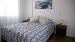 A bedroom with a bed, two bedside tables, a nightstand, a wall-mounted lamp, and a painting. - Comfortable Apartment in Palermo (Buenos Aires)