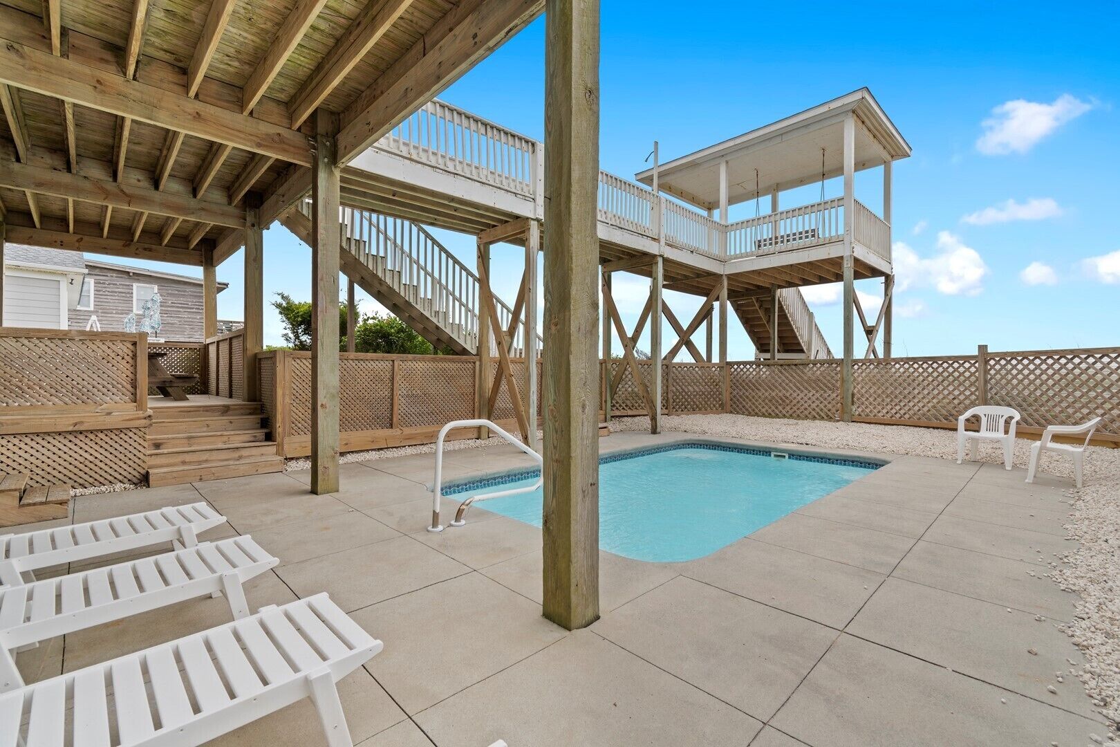 Ein Poolbereich mit Holzterrasse, Pool und überdachter Sitzgelegenheit.