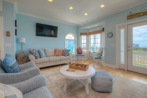 A living room with a sofa, chairs, a coffee table, and a view through a glass door.