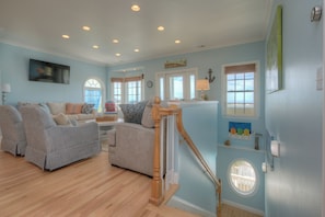 A living room with a wooden staircase, a sofa, and a dining area.