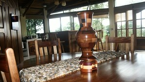 Uma mesa de jantar de madeira com um caminho de textura pedregosa, um vaso de madeira e cadeiras.