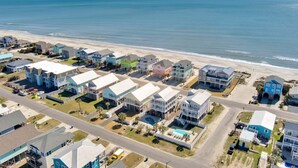 Uma área residencial costeira com casas, uma praia e céu claro.