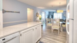 Cozinha com lava-louças Bosch, sala de jantar com cadeiras, mesa e lustre.