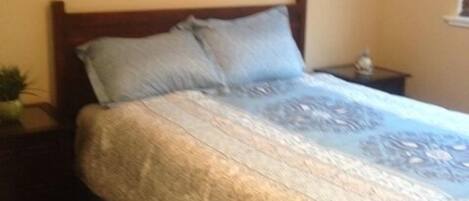 Un dormitorio con cama, mesita de noche y ventana.