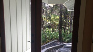 Eine Holztür mit Fensterglas, die zu einem Garten mit Kiesweg und Baum führt.