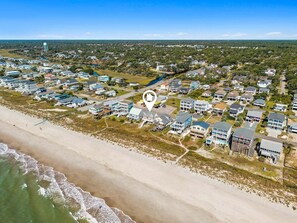 An aerial view of a coastal residential area with houses, a beach, and a water tower. - Direct Oceanfront Home | Sleeps 12 with Stunning Views | Atlantic Breeze (Oak Island)