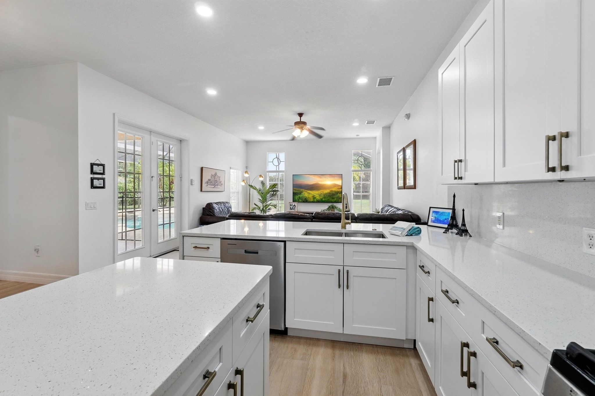 A modern kitchen with white cabinetry, a stainless steel dishwasher, and a large island with a sink.