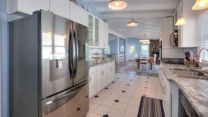 Una cucina moderna con elettrodomestici in acciaio inossidabile, mobili bianchi e luci a sospensione.
