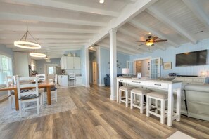 A spacious kitchen with wooden flooring, white cabinetry, and pendant lighting. - Isle Be Seaing You: Pool, Hot Tub, Beach Walk (Oak Island)