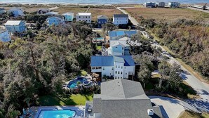 Una zona residenziale sulla costa con diverse case, una piscina e vista sull'oceano.