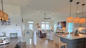 A spacious kitchen with a central island, wooden flooring, and pendant lighting. - A Toast at the Coast: Luxury oceanview home in Oak Island, featuring 5 kings, private heated pool. (Oak Island)