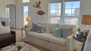 A living room with a beige sofa, a brown leather couch, and a coffee table with decorative items. - A Toast at the Coast: Luxury oceanview home in Oak Island, featuring 5 kings, private heated pool. (Oak Island)
