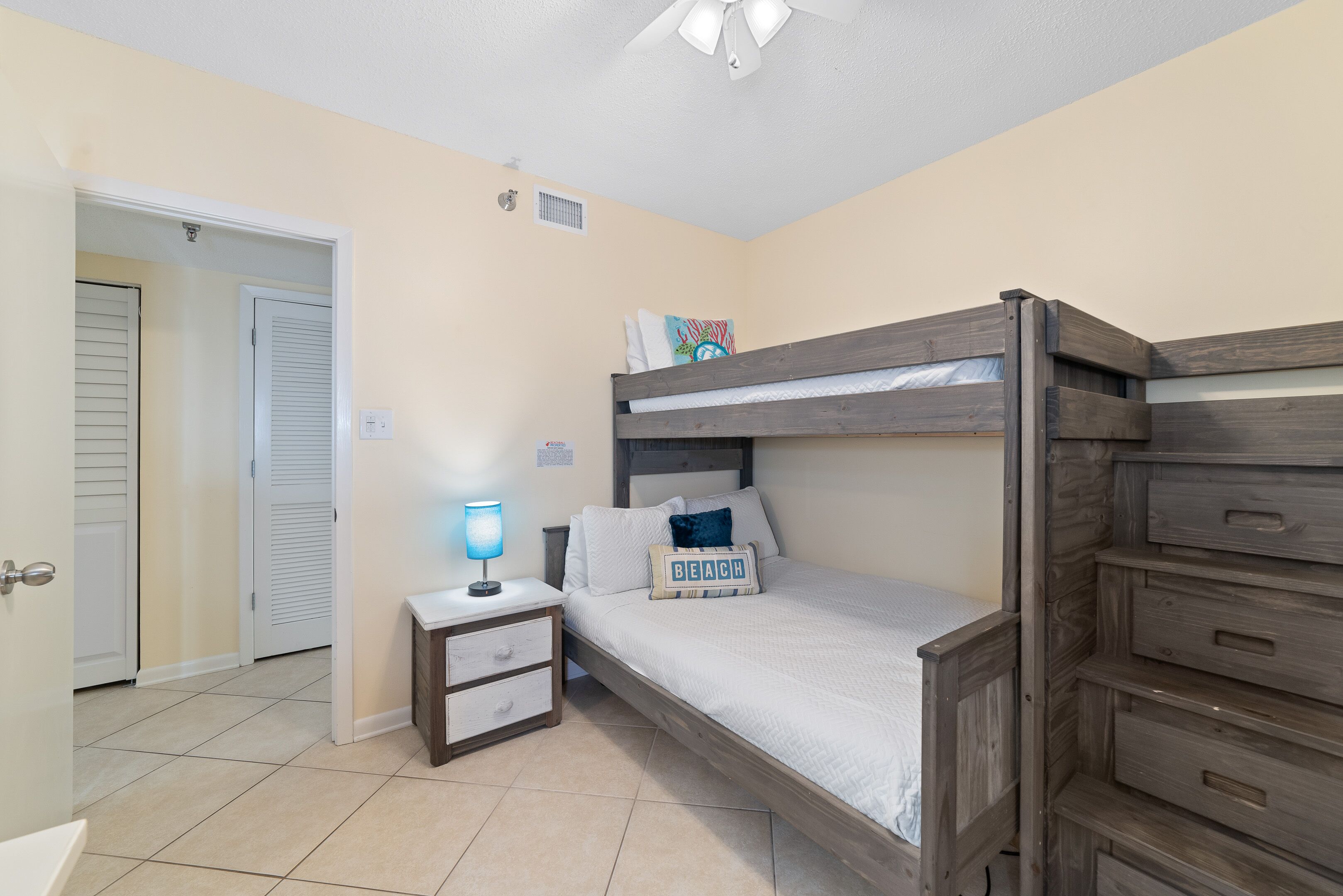 A bedroom with a bunk bed, a bedside table with a lamp, and a nightstand.