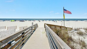 A wooden boardwalk leading to a sandy beach with an American flag. - DIRECT GULF FRONT, AWESOME BEACHES, GREAT AMENITIES, ORANGE BEACH ACTIVITIES (Orange Beach)