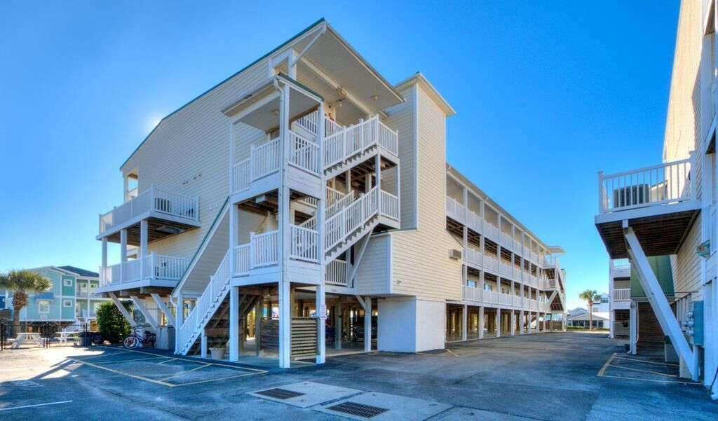 A multi-story hotel with a central staircase, balconies, and a parking area.
