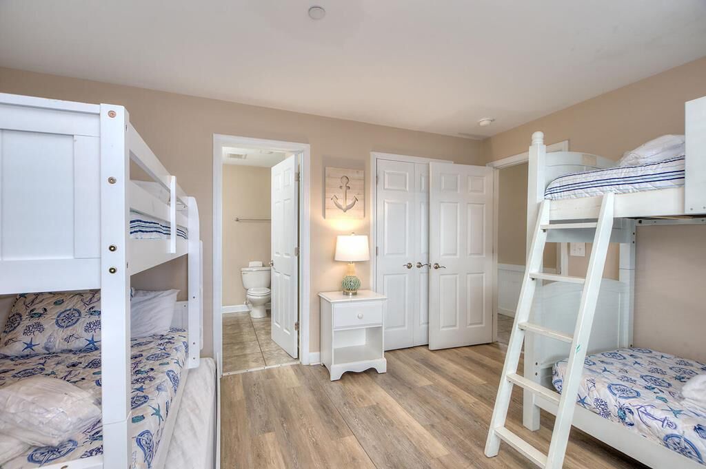 Une chambre avec des lits superposés, une petite table de chevet avec une lampe et une armoire.