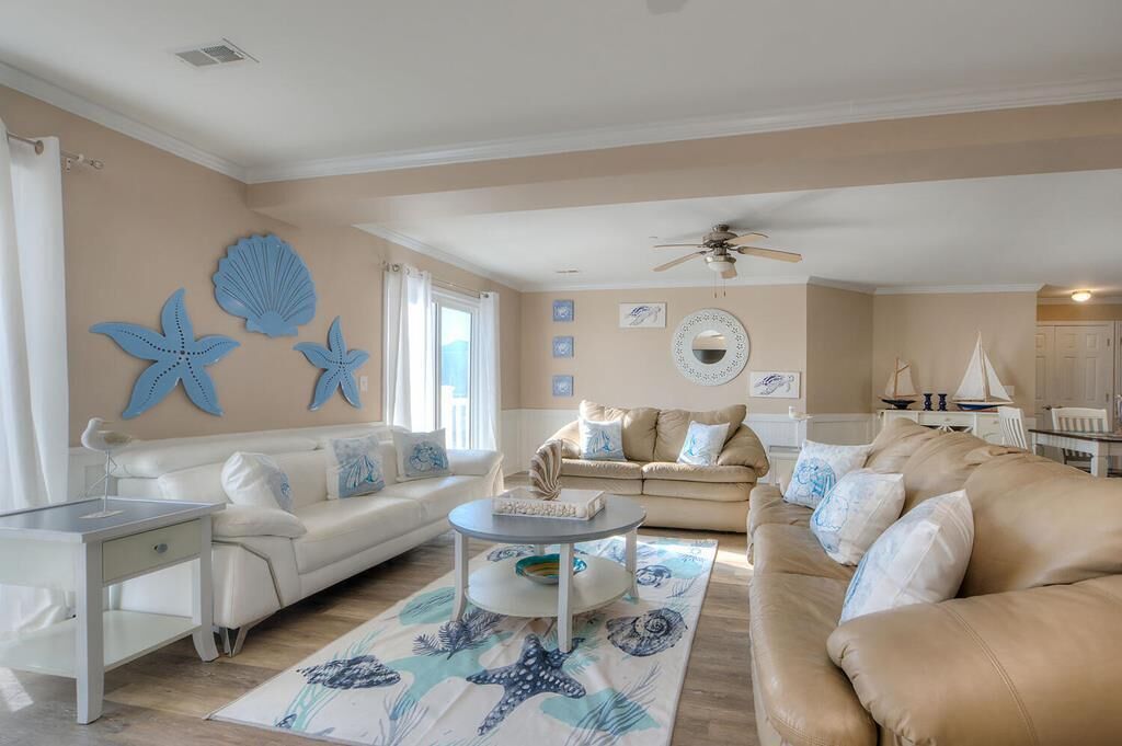 A spacious living room with two sofas, a coffee table, and decorative starfish wall art.