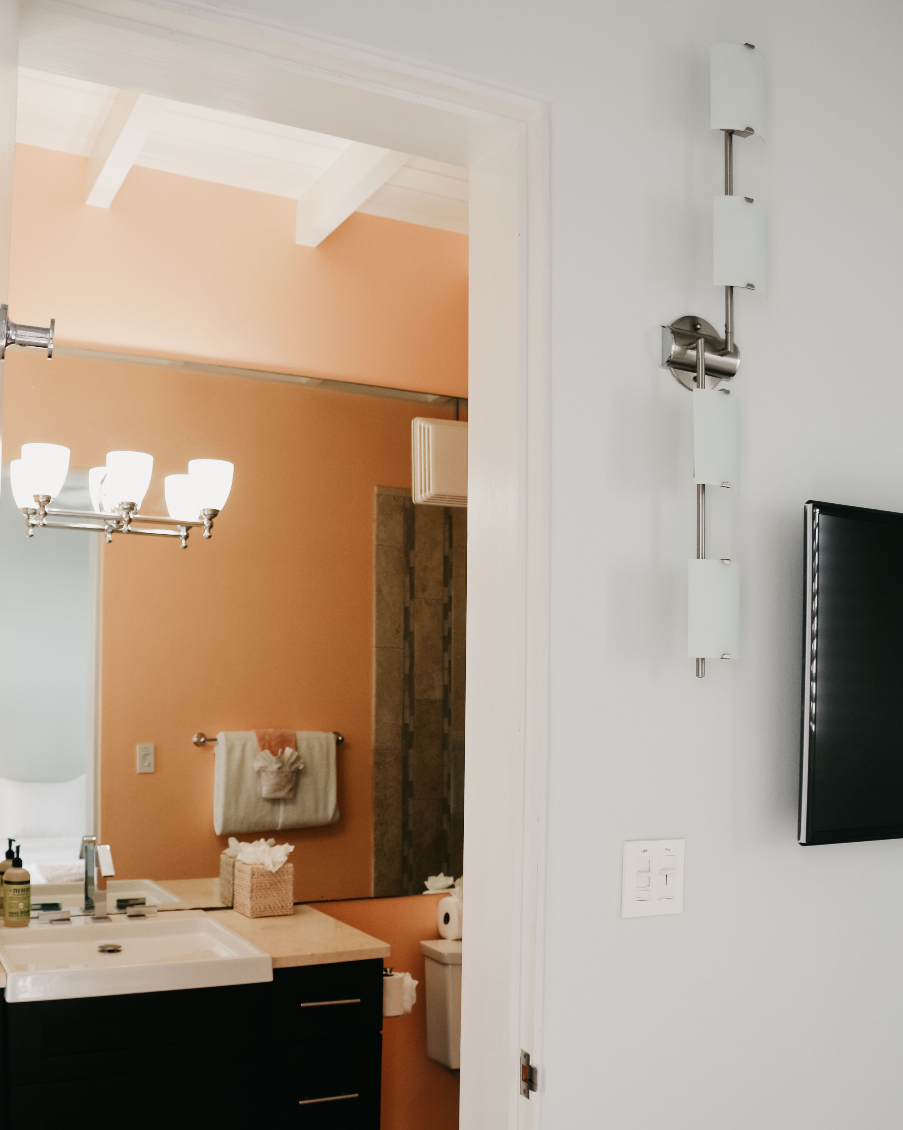 A bathroom with a sink, mirror, towel rack, and a wall-mounted light fixture.