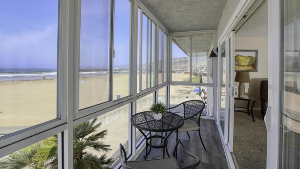 Un balcon donnant sur la plage, une table avec des chaises et une lampe.