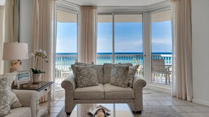 A living room with a beige sofa, a glass coffee table, and a view of the ocean through large windows. - St. Croix  #805, Awesome View From Every Room! (Destin)