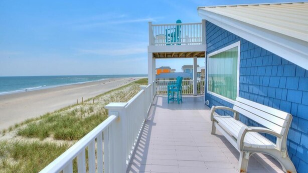 A balcony with a view of the beach, a bench, and a table with chairs. - Experience oceanfront bliss at Summer Wind West in Oak Island! Ideal for 12 guests. (Oak Island)