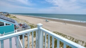 A beach view from a balcony with a view of the ocean and a sandy beach. - Experience oceanfront bliss at Summer Wind West in Oak Island! Ideal for 12 guests. (Oak Island)