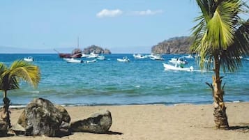 Una playa con barcos, palmeras y cielo despejado.