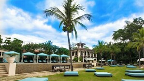 A resort with a pool area, lounge chairs, and a building with a distinctive architectural style. - Stunning Ocean View from Luxury Two Bedroom in Pacifico  - Perfect Coco Location (Playa del Coco)