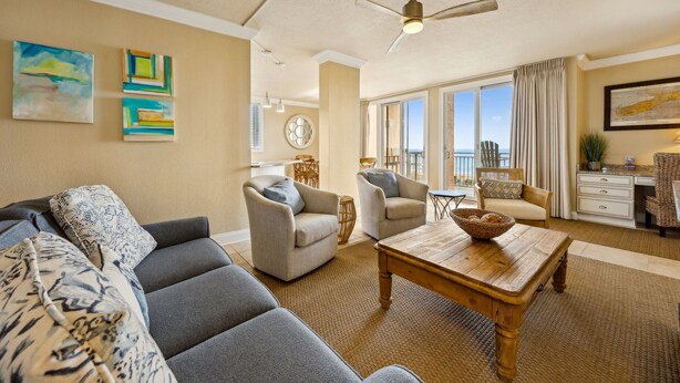 A living room with a gray sofa, two armchairs, a wooden coffee table, and a ceiling fan. - Oceanfront 3br/3ba Shipwatch Villa, Oceanfront (Fernandina Beach)