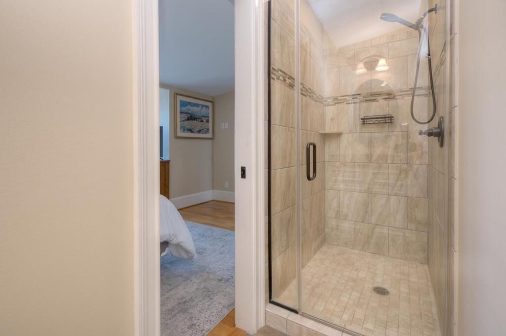 Une salle de bain moderne avec une douche à parois de verre, une baignoire blanche et un plancher en bois.