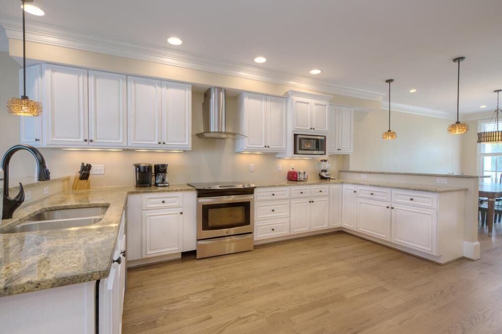 A modern kitchen with white cabinetry, stainless steel appliances, and pendant lighting.