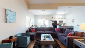 A living room with a sectional sofa, a coffee table, a side table, and a painting on the wall.