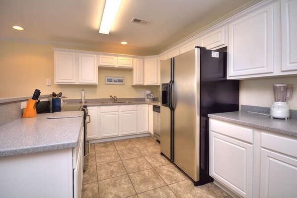 A modern kitchen with white cabinets, stainless steel appliances, and a granite countertop. - Discover ocean views at OW 2203, a cozy 2BR condo in Oak Island for unforgettable getaways. (Oak Island)