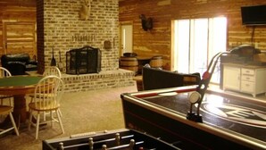 A rustic room with a brick fireplace, wooden walls, a billiards table, and a television mounted on the wall. - Have it All!!! True Water Front, Amazing Views (Golden)