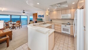 Una cocina moderna con una isla grande, un área de comedor con vistas y un ventilador de techo.