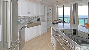 A modern kitchen with white cabinets, a stainless steel range, and a view of the ocean. - Sunshine Daydream-Panoramic Gulf Views from Every Room! Beach Chair Svc Included (Miramar Beach)