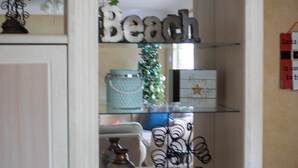 A room with a white cabinet, a Christmas tree, and a shelf with decorative items.