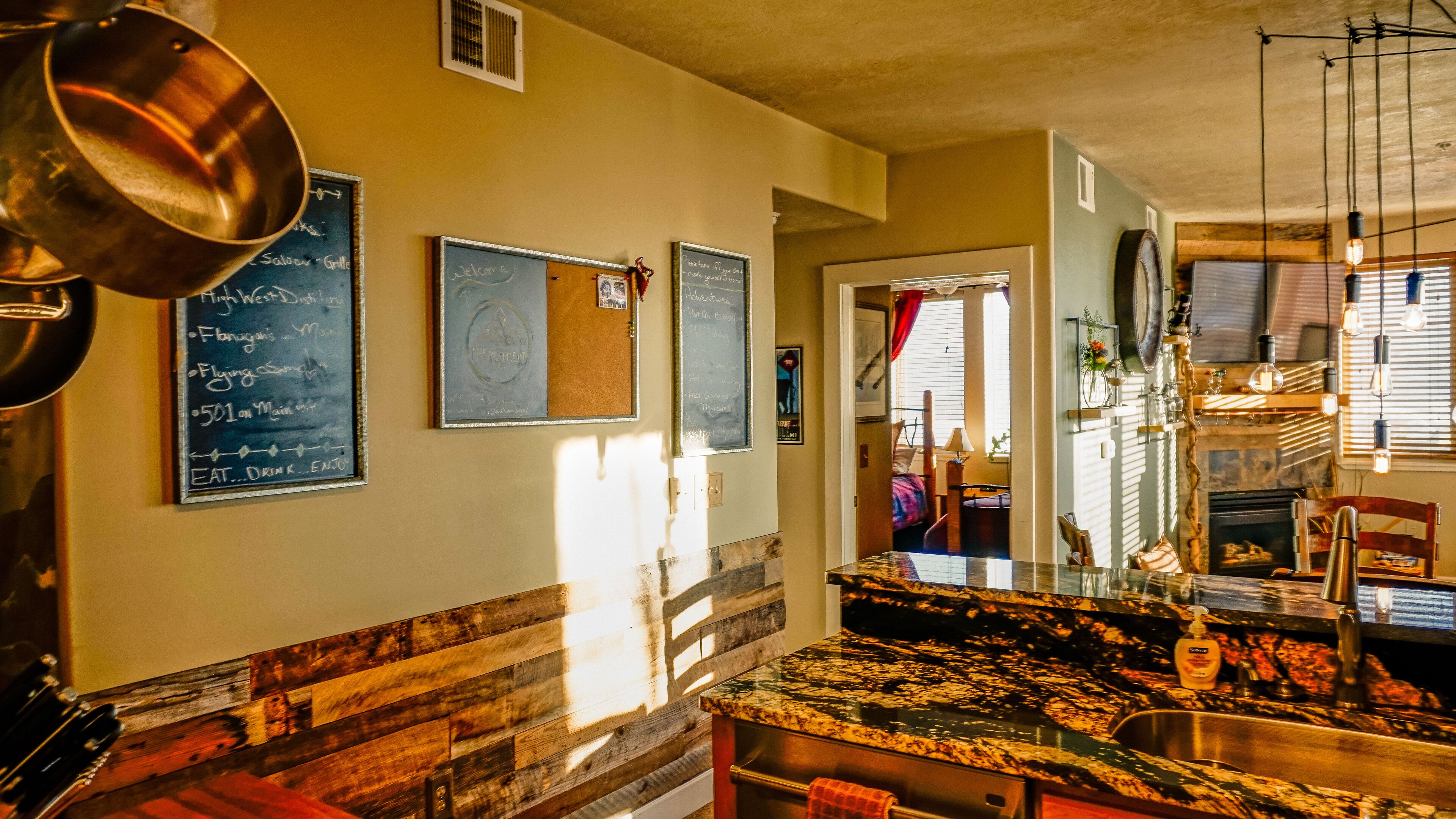 A restaurant interior with a wooden bench, a marble countertop, and a chalkboard menu.