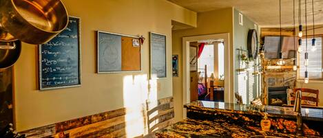 A restaurant interior with a wooden bench, a marble countertop, and a chalkboard menu.