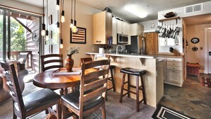 A kitchen with wooden cabinets, a central island, bar stools, and pendant lighting.