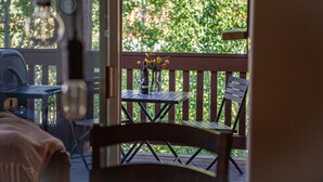 A wooden deck with a table and chairs, a grill, and a bottle of wine.