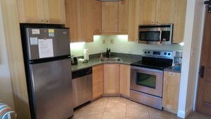 A kitchen with wooden cabinets, a stainless steel refrigerator, a microwave, and an oven. - Hidden Beach Hideaway — 200 Yards to Sand, Free Bikes, Pool & WiFi (Seagrove Beach)