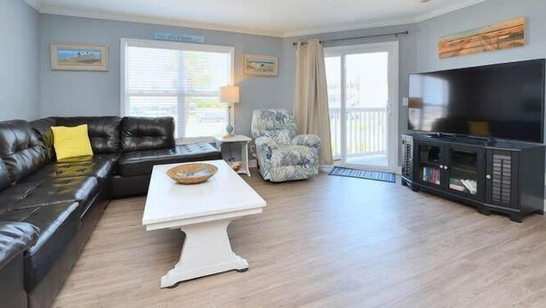 Een woonkamer met een bank, fauteuil, televisie en salontafel.