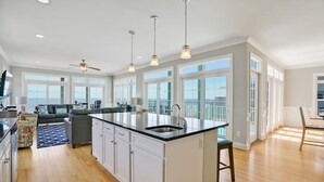A spacious kitchen with a large island, white cabinetry, and a view to the outside. - Discover oceanfront bliss at 7th Heaven in Oak Island, NC—spacious 7BR, sleeps 24! (Oak Island)