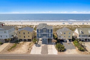 A beachfront residential area with houses, a sandy beach, and the ocean in the background.