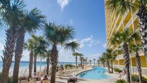 A pool area with palm trees, lounge chairs, and a view of the ocean.