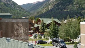 A mountain lodge with a parking lot, surrounded by forested mountains.