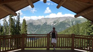 A wooden deck with a view of mountains and trees.